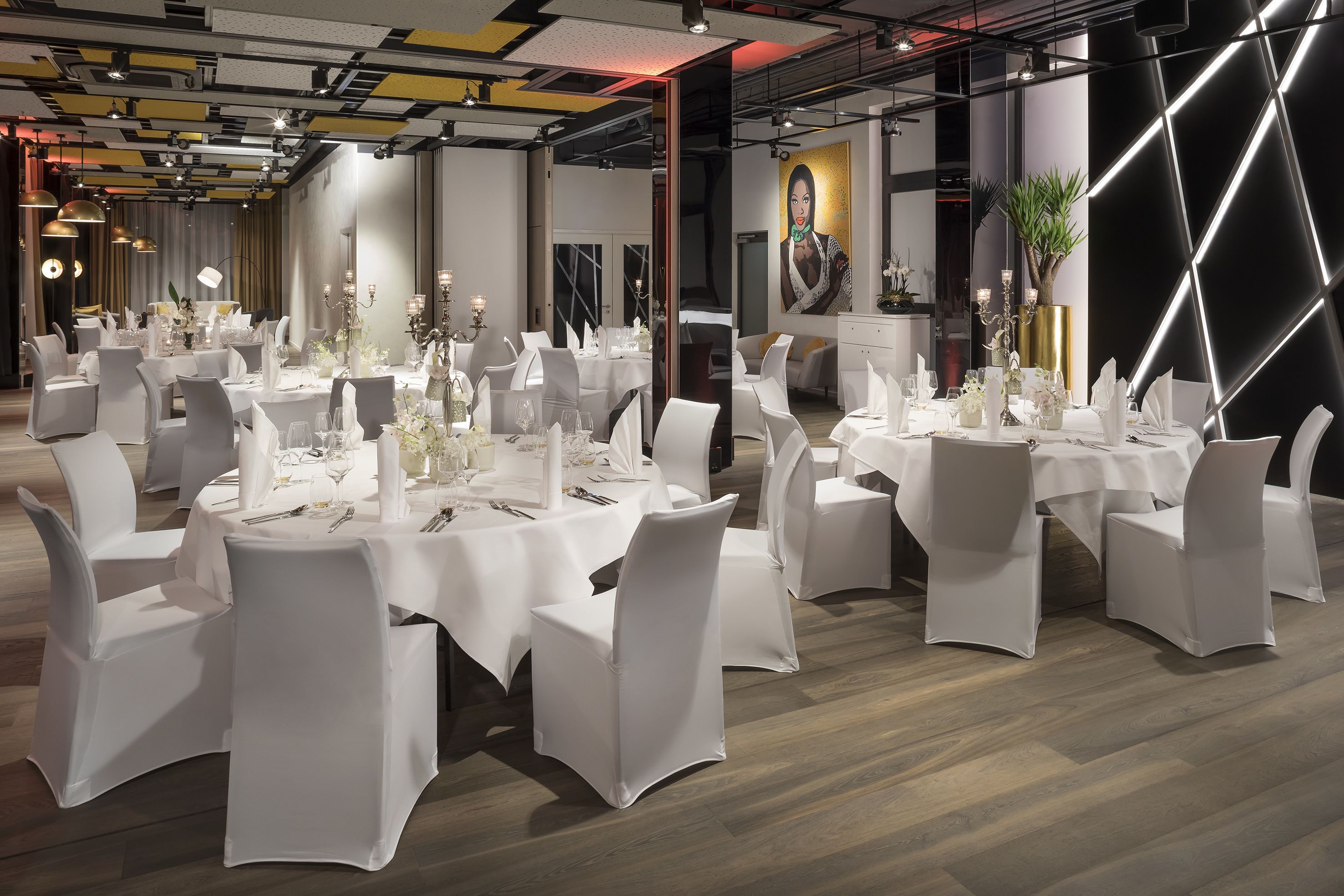 A modern dining area with round tables, white tablecloths, and matching chairs.