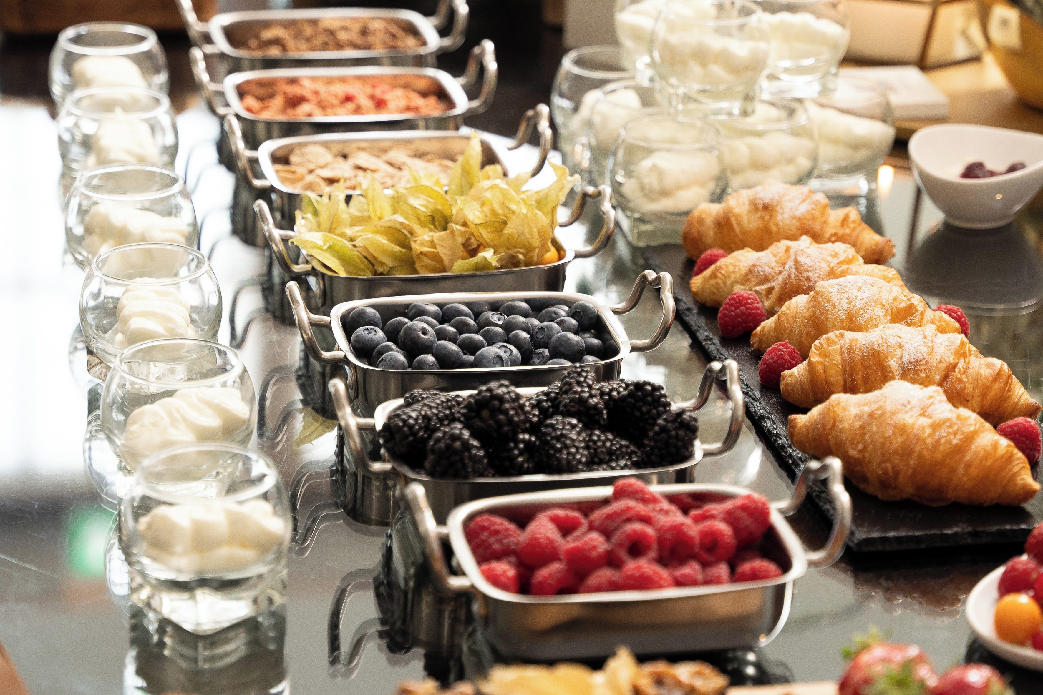 Ein Buffet mit verschiedenen Speisen, darunter Obst, Backwaren und Milchprodukten.