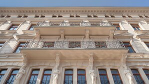 Fachada de edificio con elementos arquitectónicos clásicos, incluyendo columnas y balcones ornamentados.