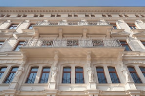 Een gevel van een gebouw met klassieke architecturale details, zoals zuilen en versierde balkons.