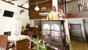 Een eetgedeelte met houten meubels, een aan de muur bevestigde televisie en een decoratieve kast met bloemen.