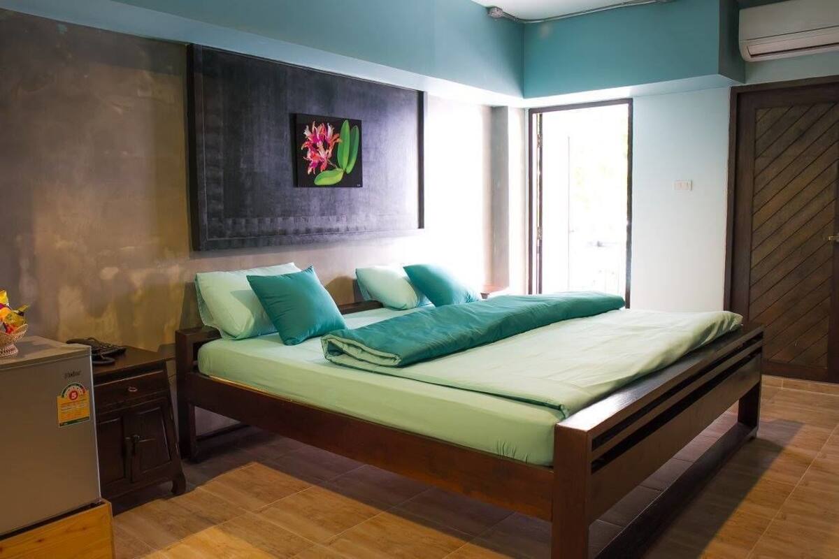 Quarto com cama, mesa de cabeceira, cômoda e ar-condicionado fixado na parede.