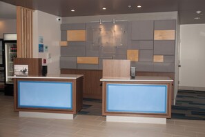 A reception area with two reception desks, a wall-mounted security camera, and a sign indicating check-in and check-out times. - Holiday Inn Express & Suites Decatur by IHG (Decatur)