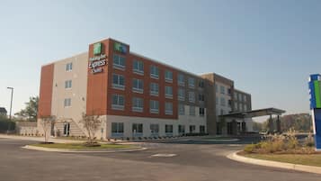 Un hotel Holiday Inn Express & Suites con un diseño arquitectónico moderno, que presenta un techo plano y una fachada combinada de ladrillo y vidrio.