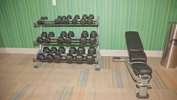A gym with a bench and a rack of dumbbells.