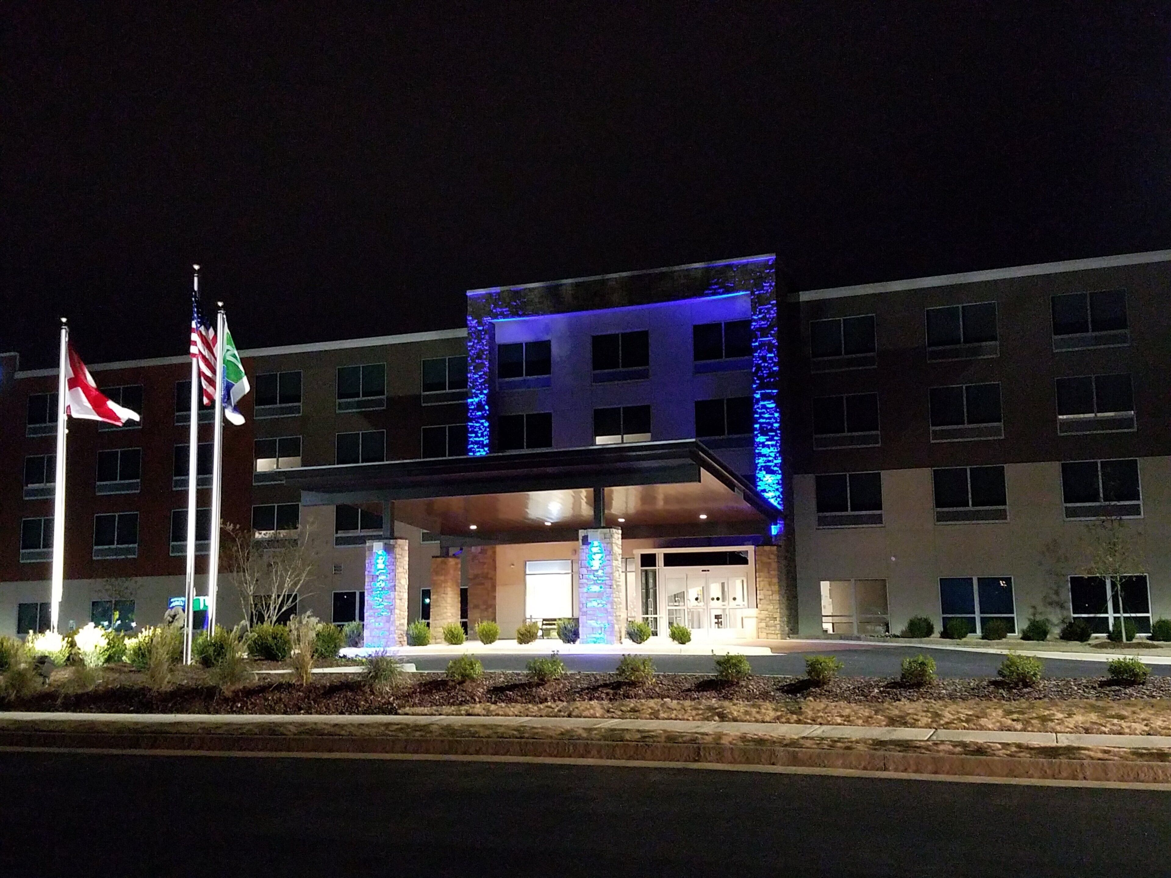A hotel with a modern entrance, multiple flags, and illuminated blue accents.