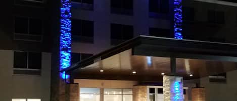 Um hotel com fachada moderna, amplas janelas e área de entrada coberta.