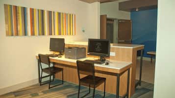 A workspace with two desks, chairs, computers, and a colorful abstract painting on the wall.