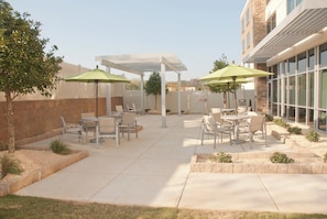 An outdoor patio area with tables and chairs, umbrellas, and a pergola structure. - Holiday Inn Express & Suites Decatur by IHG (Decatur)