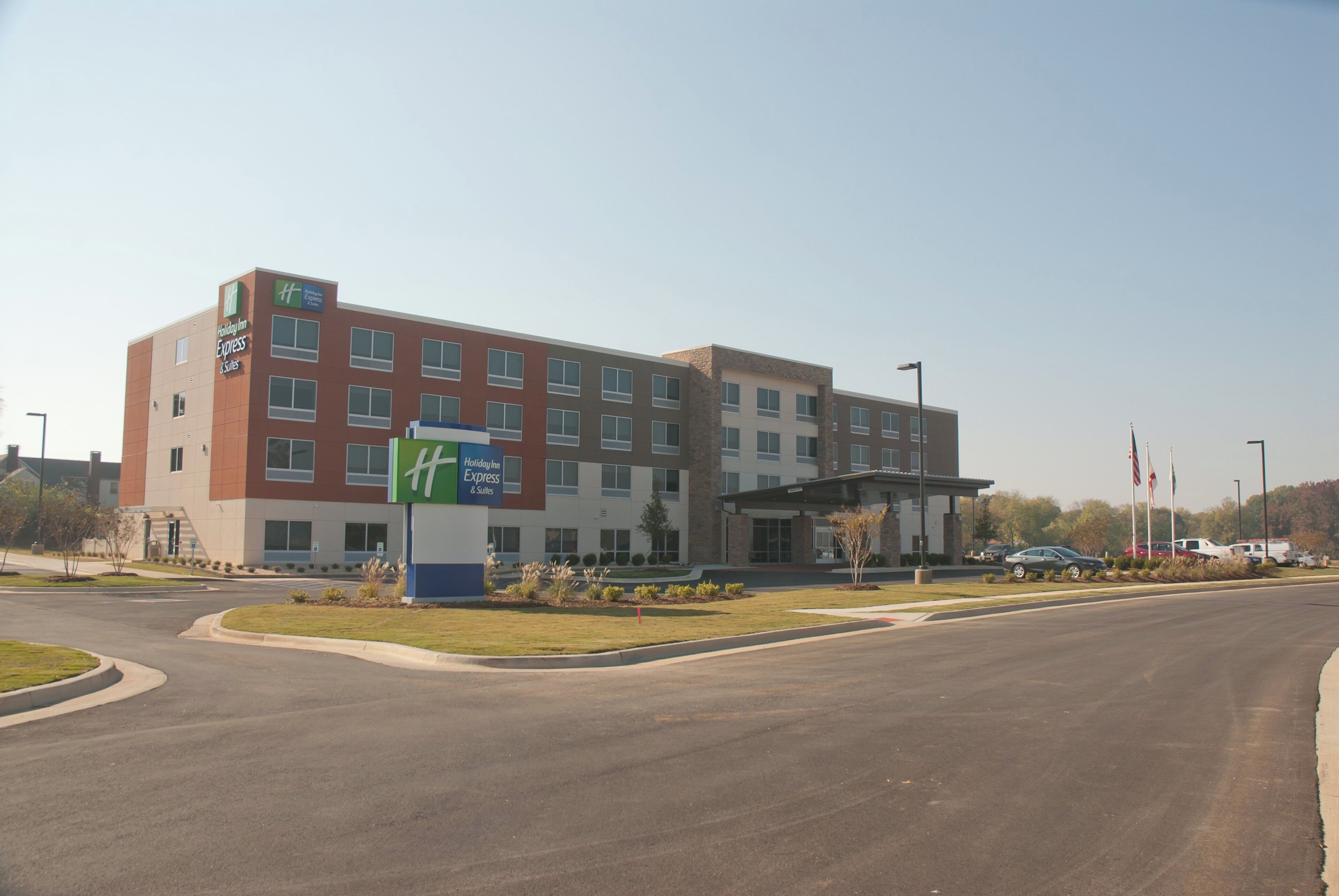 A Holiday Inn Express hotel with a modern design, featuring a prominent entrance and a parking lot with several cars.