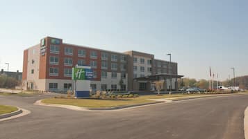 A Holiday Inn Express hotel with a modern design, featuring a prominent entrance and a parking lot with several cars.