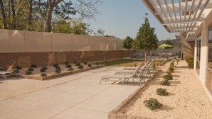 Un espace extérieur aménagé en patio, avec une pergola, des sièges et un petit jardin.