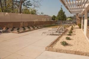 Un área de patio exterior con un pérgola, asientos y un pequeño jardín.