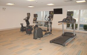 A fitness room with treadmills, ellipticals, and stationary bikes.