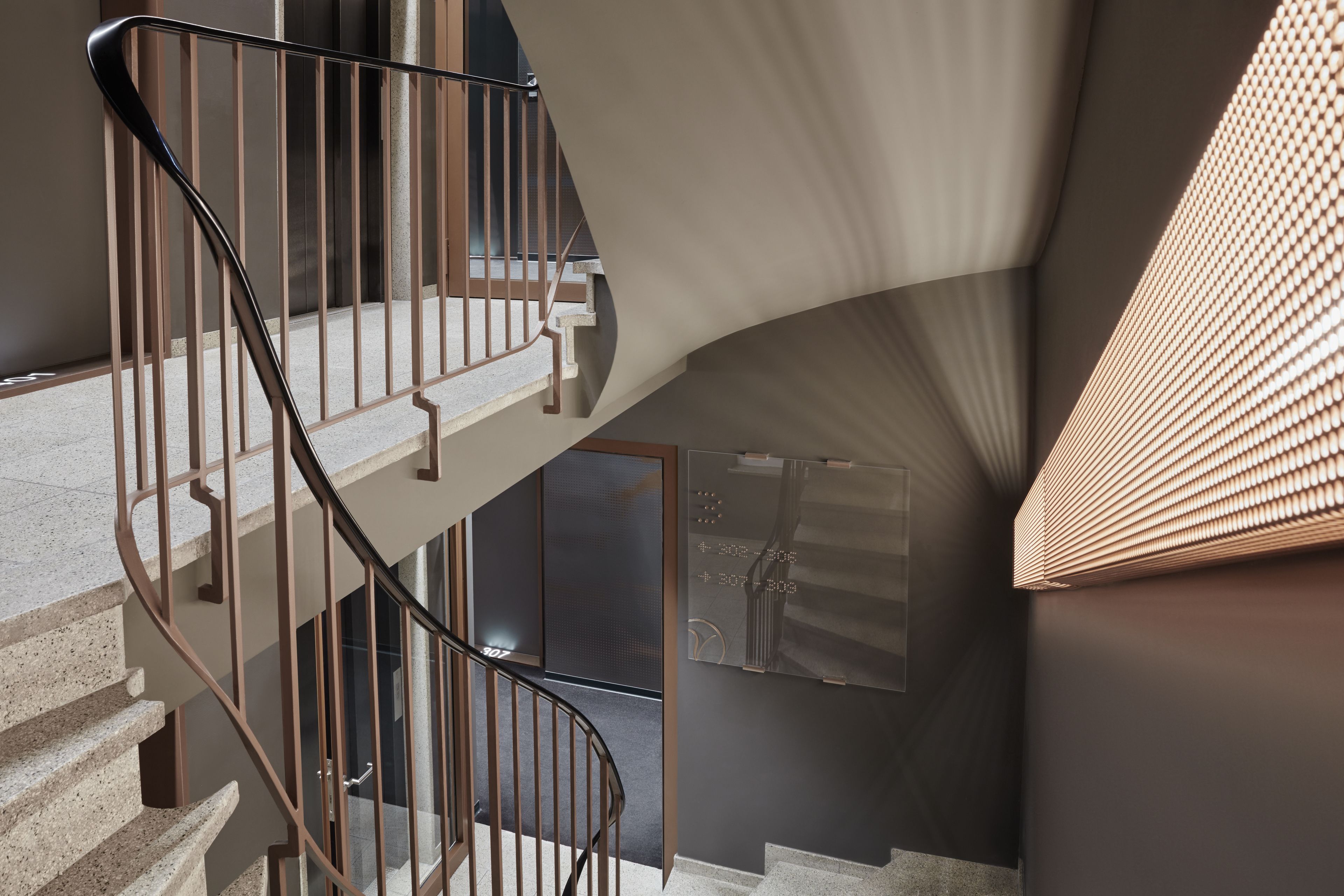 Eine moderne Treppe mit Metallgeländer und einer Glastür zu einer weiteren Ebene.