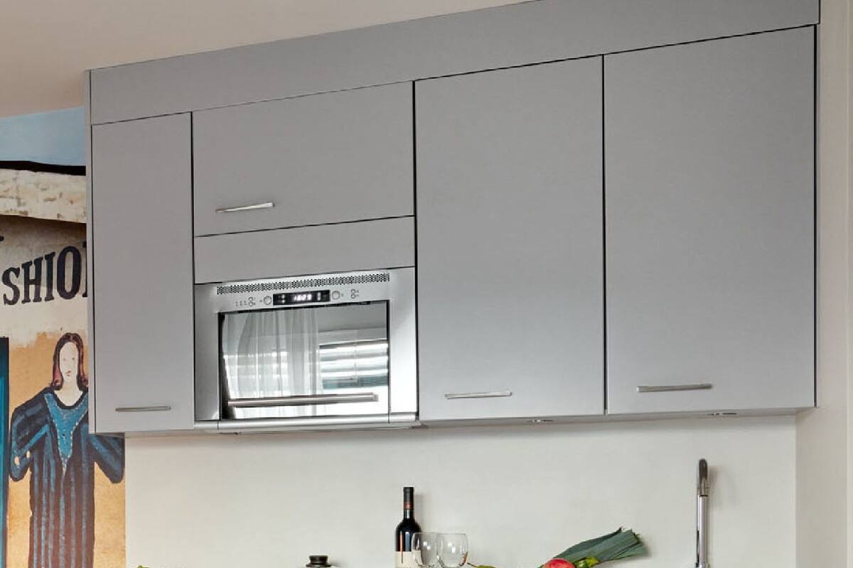 A modern kitchen with grey cabinets, a stainless steel oven, and a marble countertop.