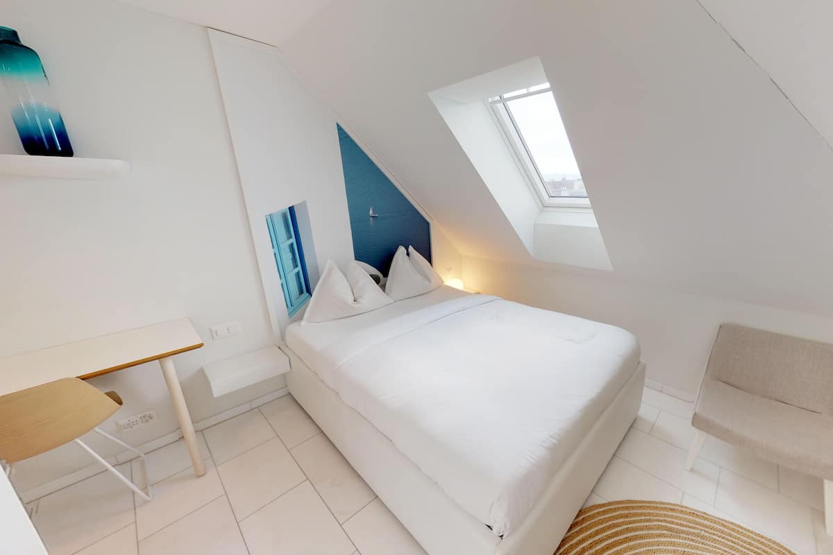 A modern, white-themed bedroom with a bed, a desk, and a chair.