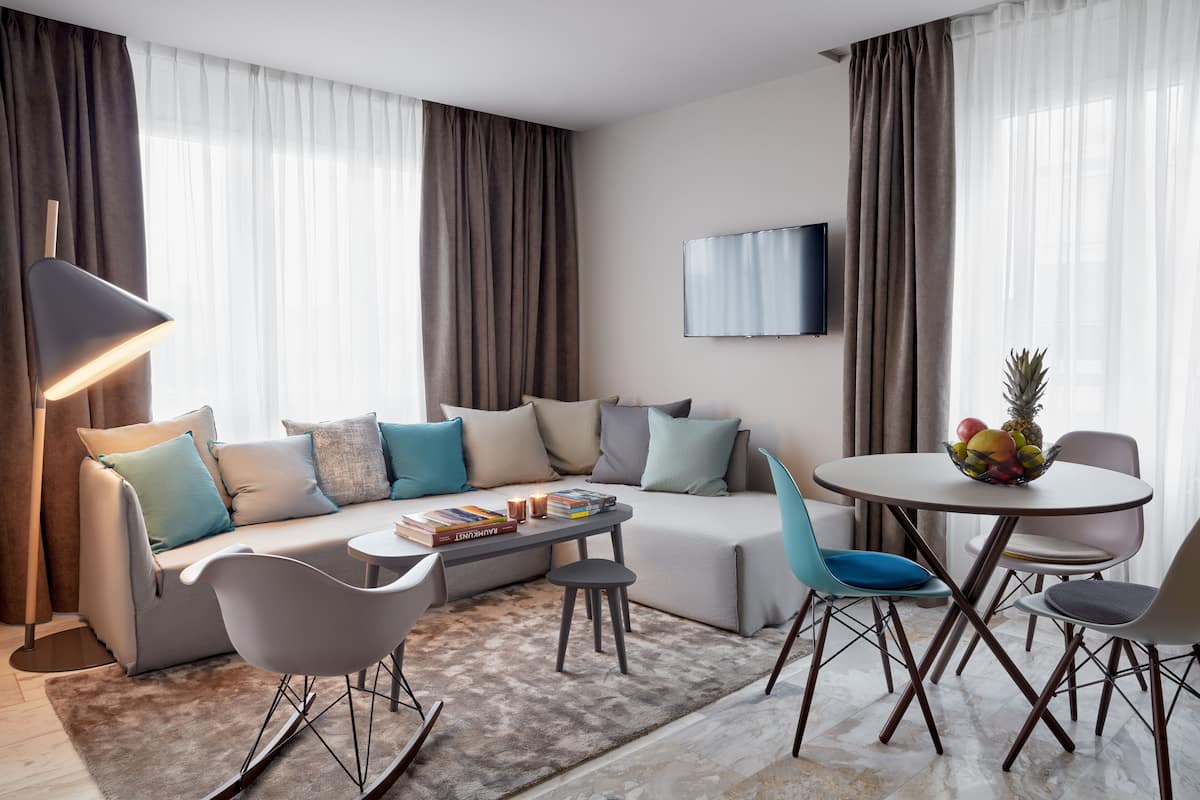 A modern living room with a sofa, chairs, a coffee table, and a TV.