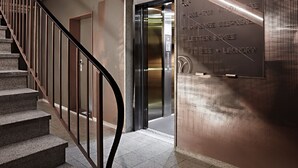 A modern elevator with a metallic finish and a glass door. - VISIONAPARTMENTS Zurich Militärstrasse (Zürich)