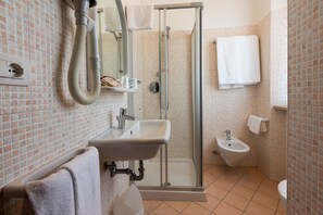 Une salle de bain dotée d’une douche à parois de verre, d’un lavabo, d’un bidet et d’un miroir.