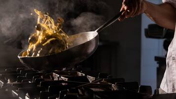 A person cooking with a pan on a stove.