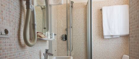 A bathroom with a glass-enclosed shower, a sink, and a mirror.