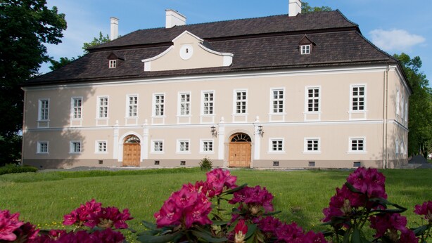 A large, two-story building with a symmetrical facade, multiple windows, and a central entrance with an arched doorway. - Zámek Jeseník nad Odrou (Jesenik nad Odrou)