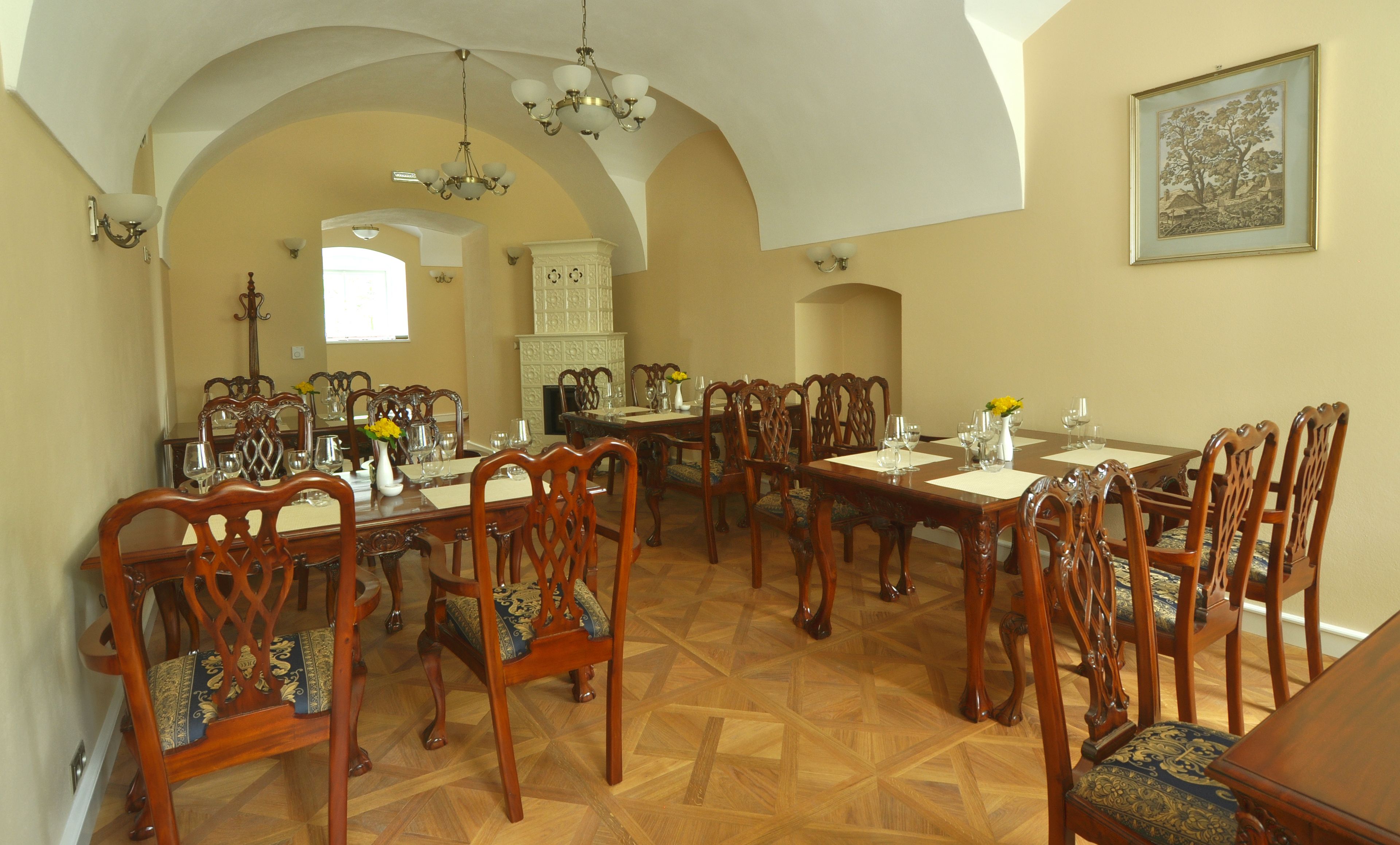 A dining area with wooden tables and chairs, a chandelier, and a fireplace.
