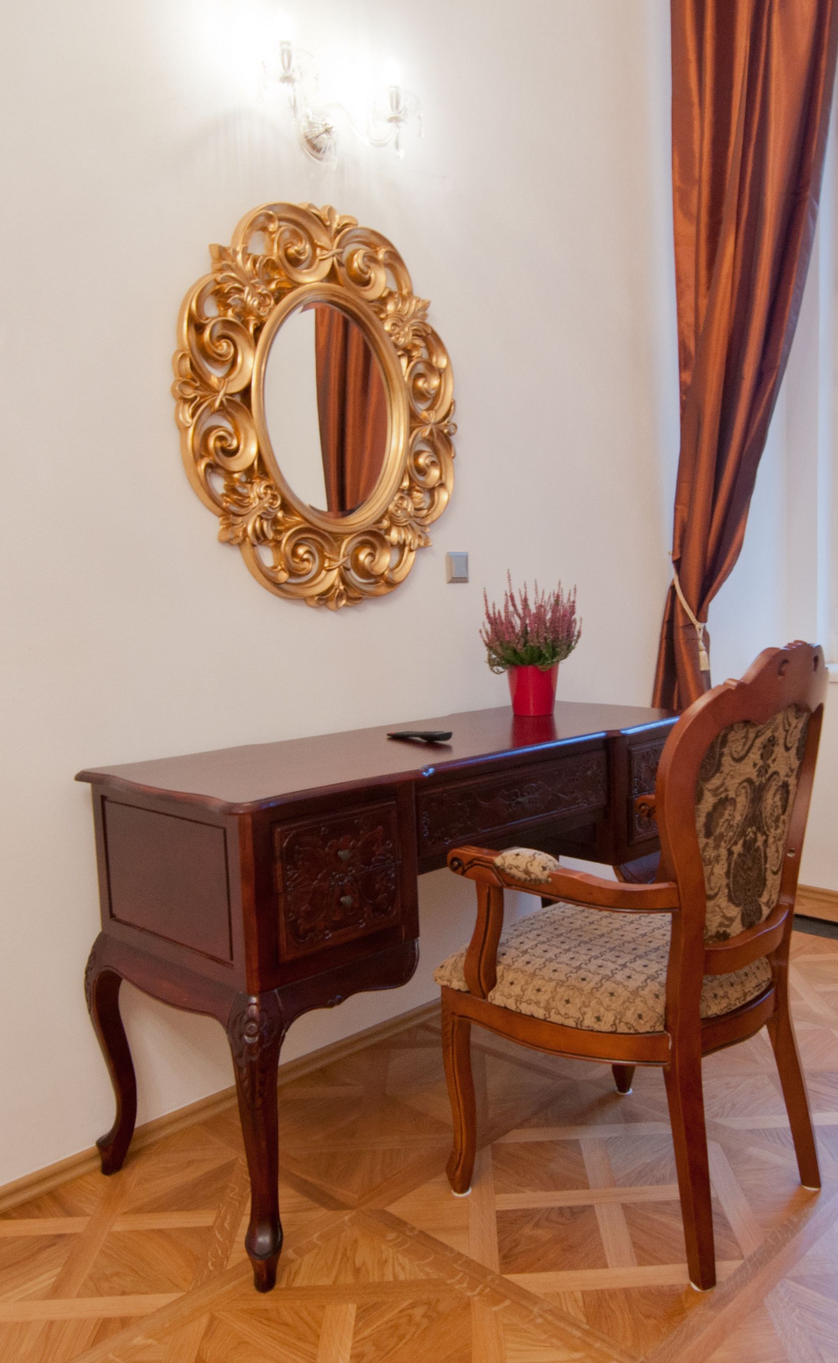 Un escritorio de madera con un espejo, una silla y una planta en maceta.