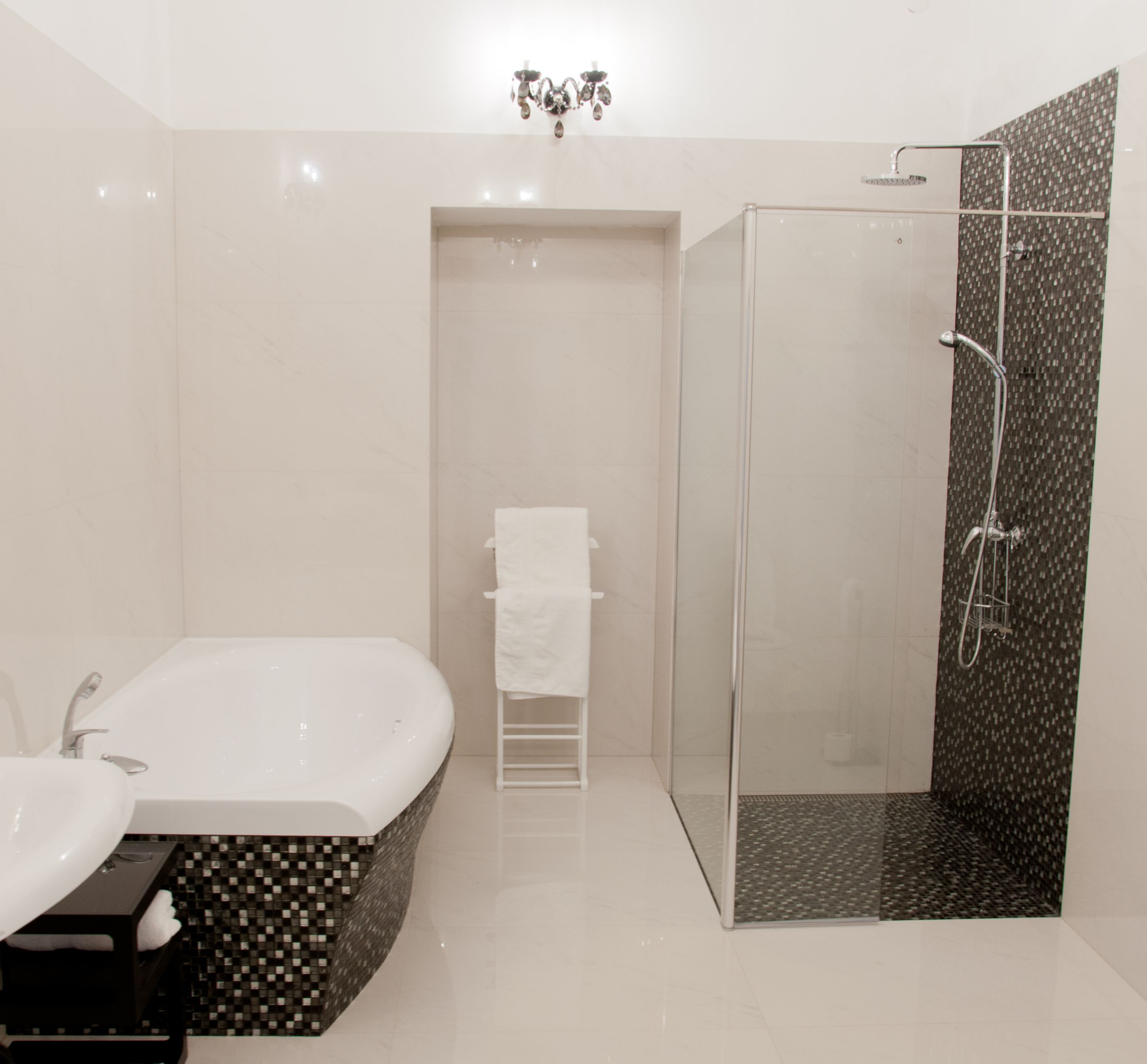 Een moderne badkamer met een vrijstaand bad, een douche met glazen wanden en een witte wastafel.