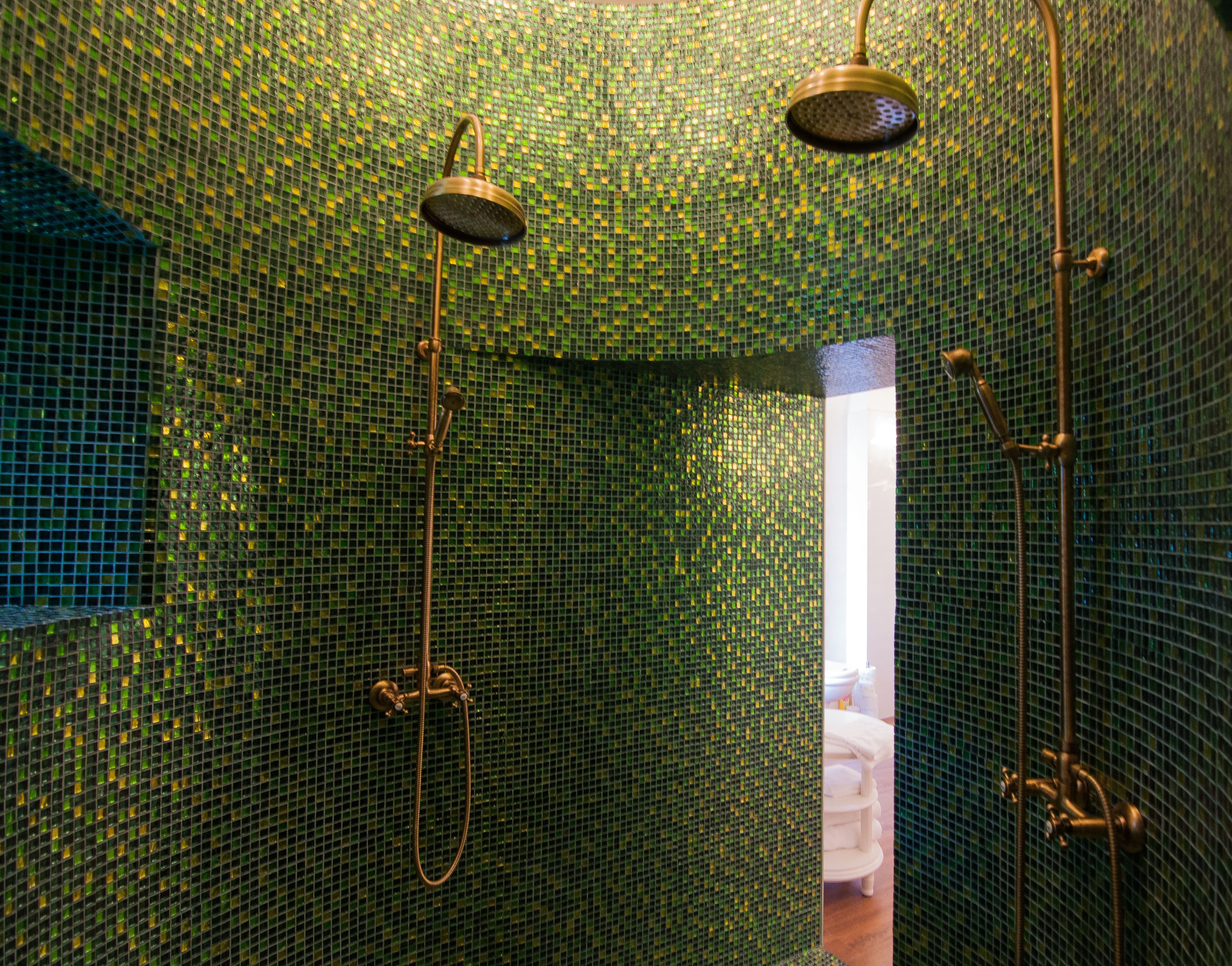 Baño con paredes de mosaico y zona de ducha con cabezal de ducha manual y fijo.