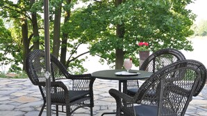 A patio with wicker chairs and a table, overlooking a body of water. - Zámek Jeseník nad Odrou (Jesenik nad Odrou)