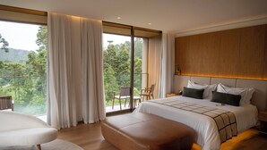 Quarto moderno com uma cama grande, cabeceira de madeira e varanda com vista para a floresta.