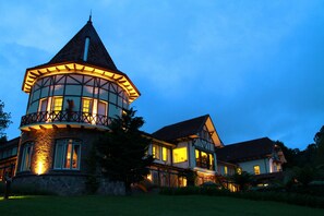 Une grande maison à plusieurs étages, dotée d’une tour imposante et d’un balcon.