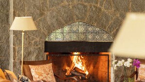 Uma sala de estar aconchegante com lareira de pedra, assentos confortáveis e uma luminária decorativa.