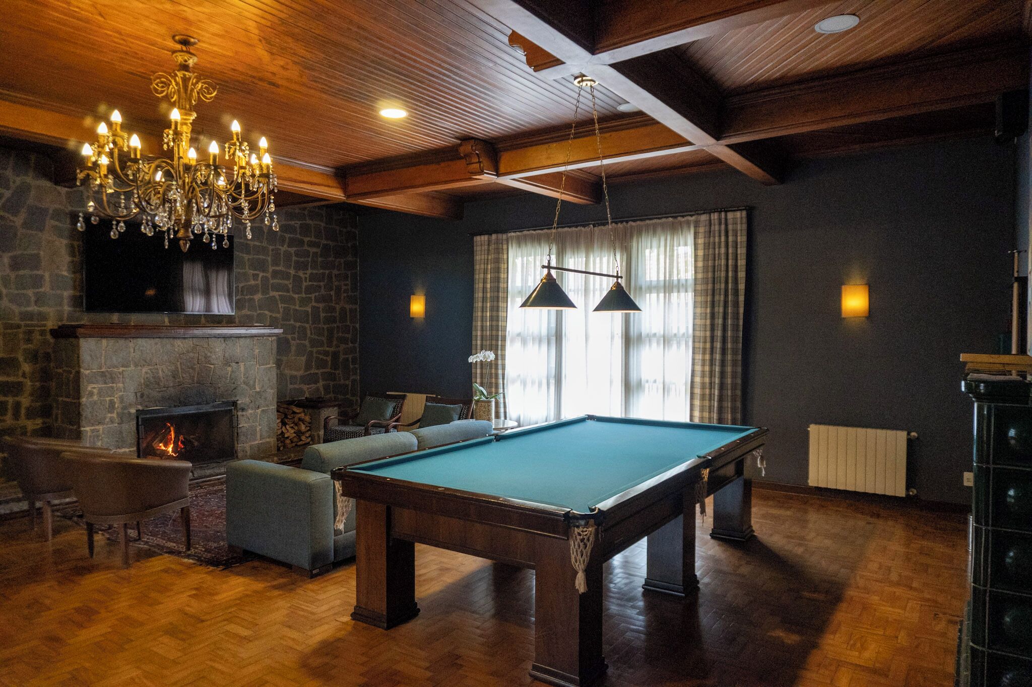 A cozy room with a pool table, comfortable seating, a fireplace, and a chandelier.