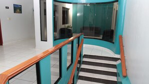 A staircase with wooden handrails and glass panels, leading to a room with a view of a building outside. - Hotel Alcala (David)