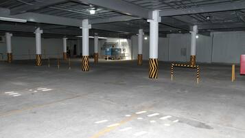 A spacious parking garage with concrete floors and white pillars.