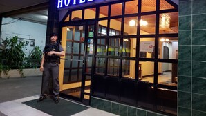 A hotel entrance with a sign reading "HOTEL ALCALA" and a security guard standing outside. - Hotel Alcala (David)