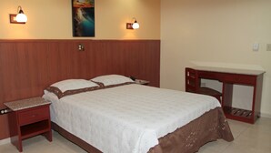 A bedroom with a bed, bedside tables, a desk, and two wall-mounted lamps. - Hotel Alcala (David)