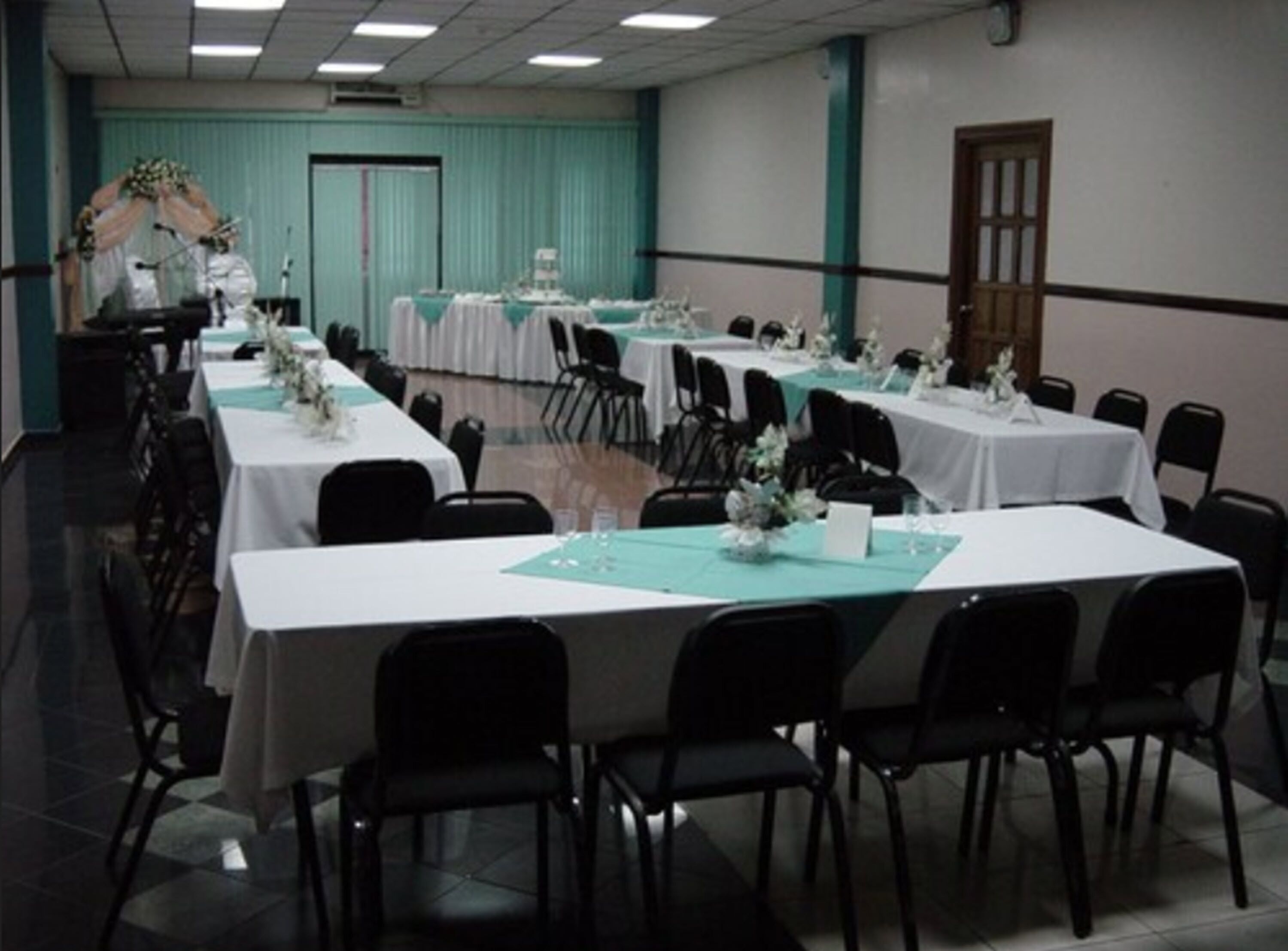 A conference room with multiple tables and chairs, arranged in rows.