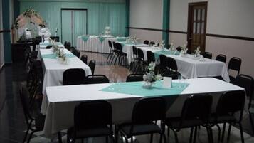 A conference room with multiple tables and chairs, arranged in rows.