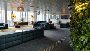 A modern lounge area with seating arrangements and a large window providing natural light.