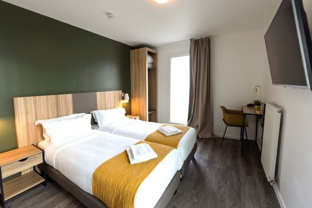 Una habitación de hotel con dos camas, un escritorio, una silla y un televisor.