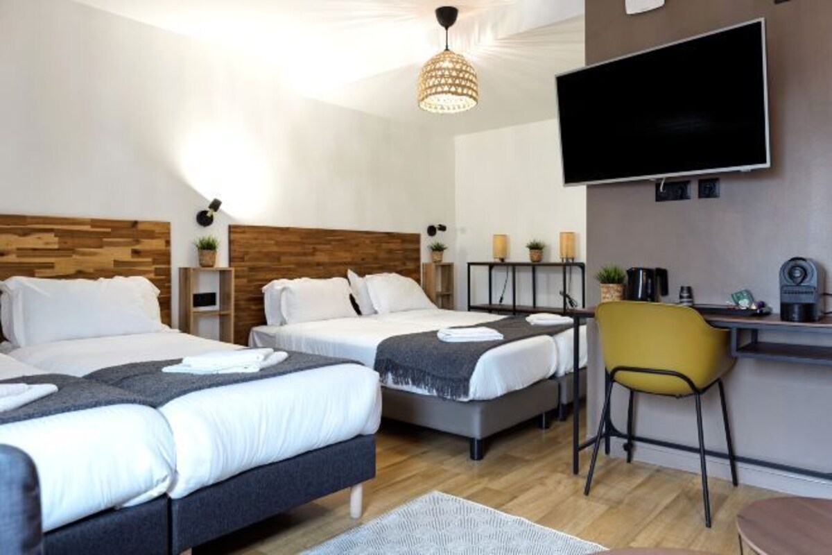 Una habitación de hotel con dos camas, un escritorio, un televisor y una silla amarilla.