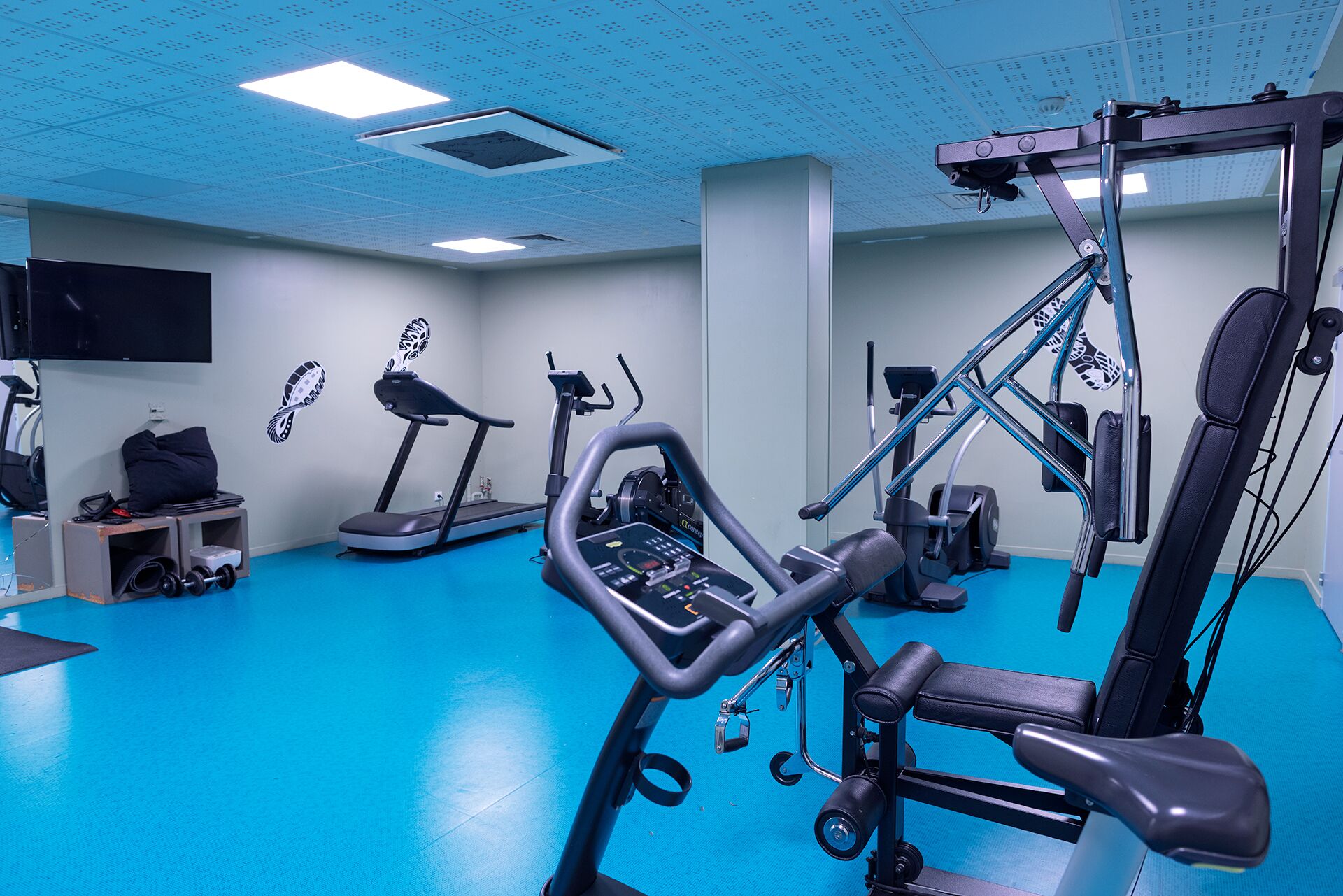 A gym with exercise equipment, a treadmill, and a weight bench.