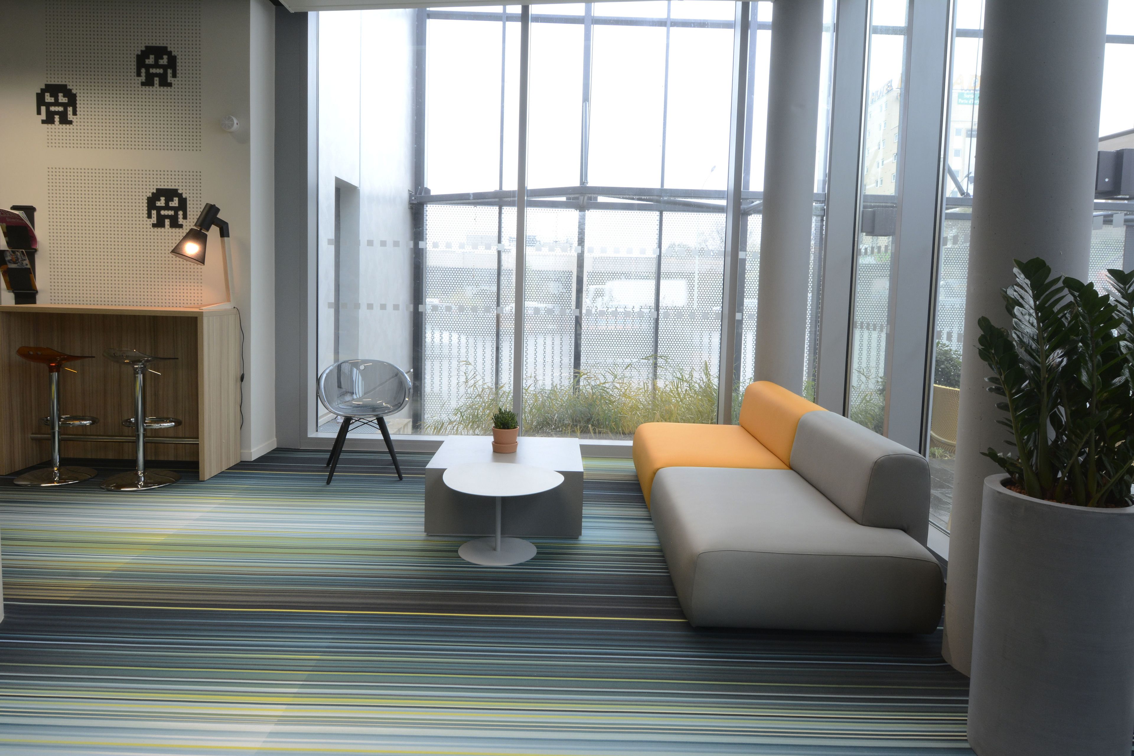 A modern room with a sofa, a small table, a chair, and a bar area with stools.