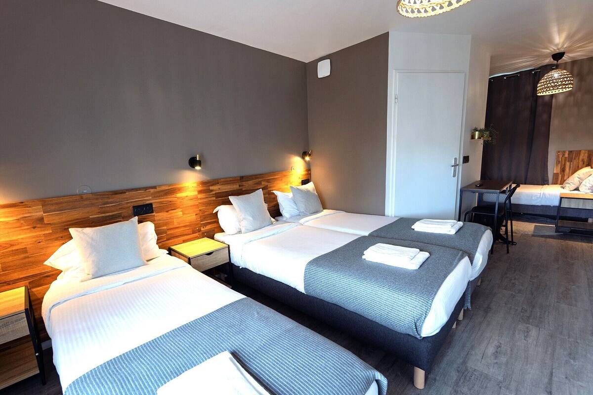 A hotel room with two beds, a desk, and a chair.