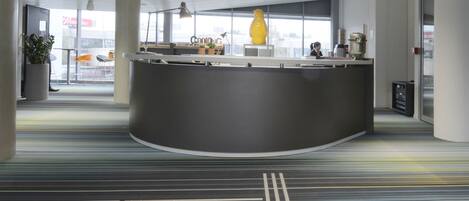 A modern reception area with a curved desk, large windows, and a striped carpet.
