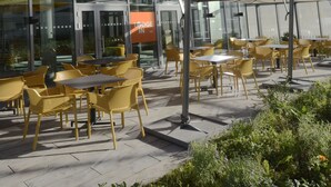 An outdoor cafe area with yellow chairs and tables, a glass building in the background, and a sign that reads "Lodge Inn".